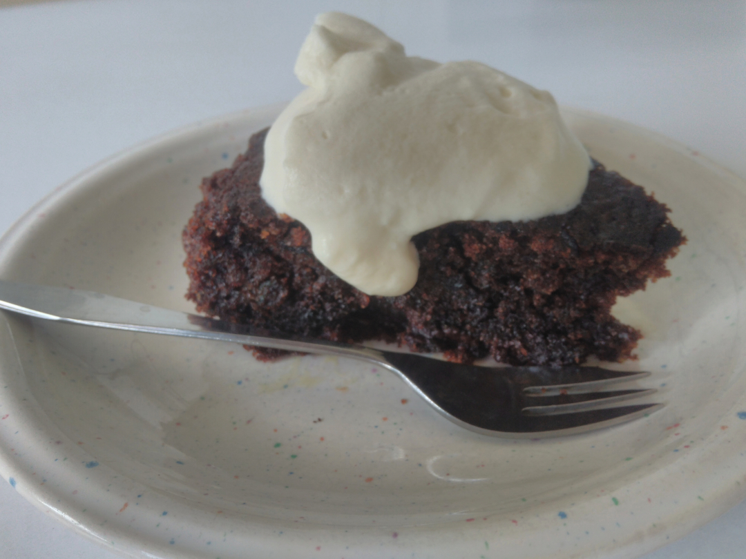 black & white, bardzo czekoladowe ciasto z bitą śmietaną na talerzyku, obok ciasta widelczyk