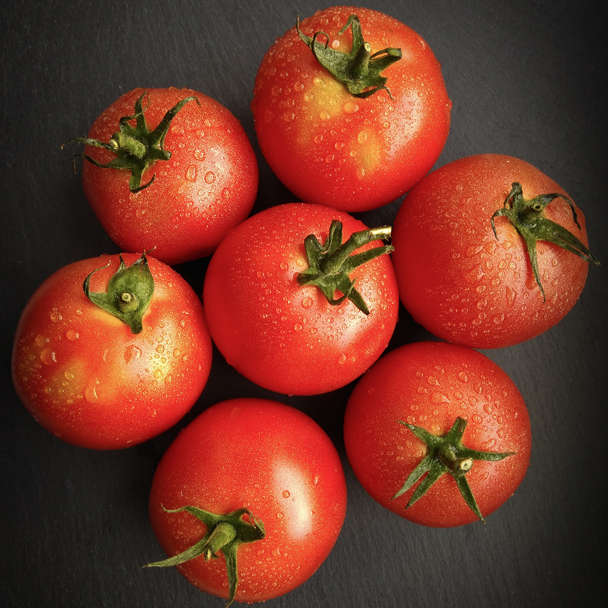 nadążamy za naturą fotografując siedem pomidorów na czarnym tle, widok z góry