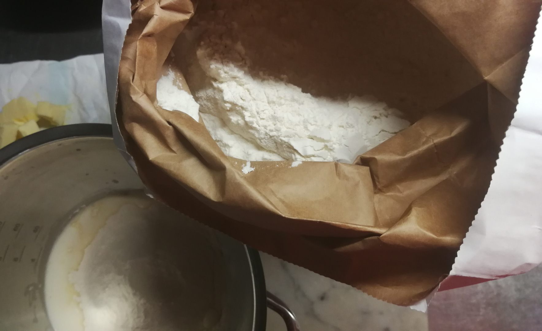 worek z mąką, w misie robota składniki na ciasto, obok masło w kostkach