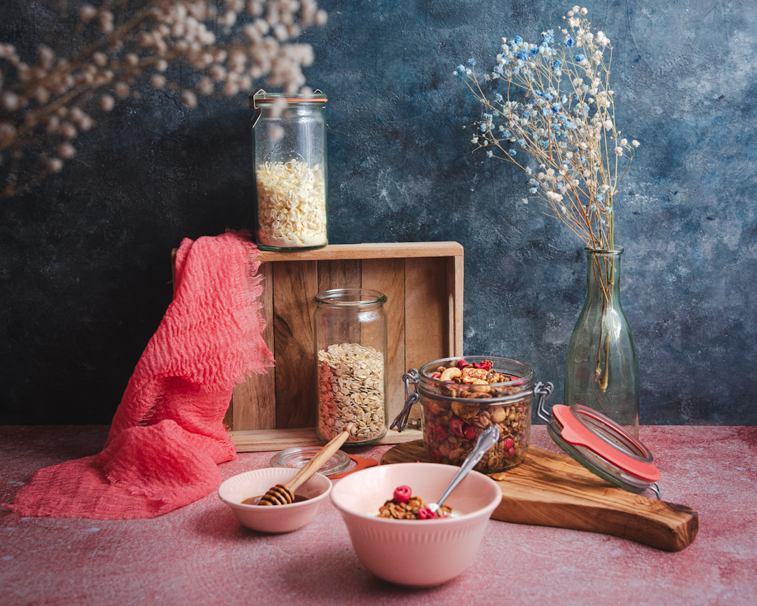 Kolorowe śniadanie - kompozycja składająca się z miski i słoika z granolą, skrzynki ze wekami i miseczki z miodem